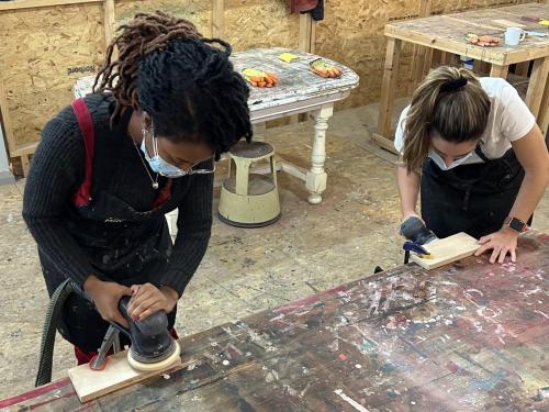 2 people working on hanging coat hooks with sanding machines in workshop diy skills